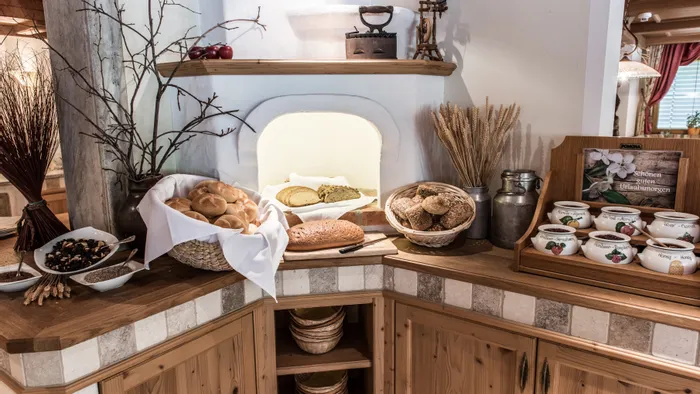 Rustikales Frühstücksbuffet mit frischen Brötchen, Müsli und beschrifteten Marmeladengläsern